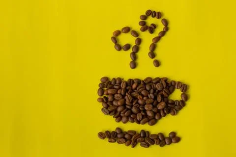 .Roasted coffee beans placed in shape of a cup on yellow background Stock Photos