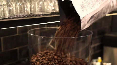 Roasted coffee beans pouring from bag into glass Stock Footage 183555170