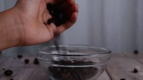 Roasted coffee beans pouring by hand into clear glass bowl 库存影片 273461954