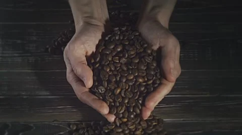 Roasted coffee beans pouring out of cupped hands Stock Footage 60362602