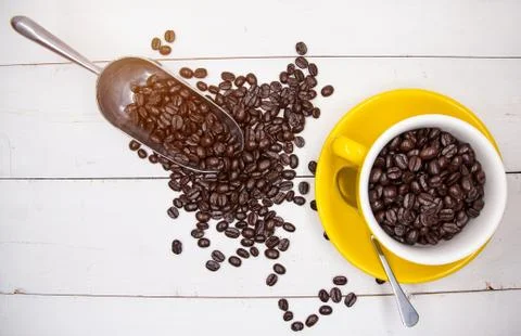 The roasted coffee beans put in ceramic cup beside coffee beans in stainless  스톡 사진