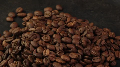 Roasted coffee beans rotating on a dark surface. Coffee beans rotate on a cast Stock Footage 308323274