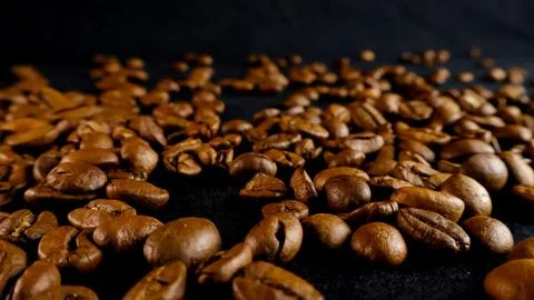 Roasted coffee beans scattered on dark studio background Stock Photos