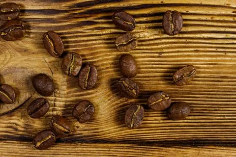 Roasted coffee beans scattered on rustic wooden table Stock Photos