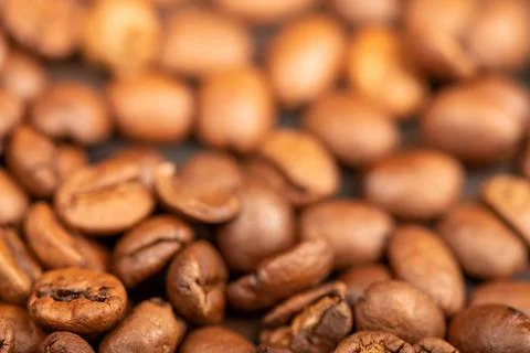 Roasted coffee beans scattered on the surface close-up, selective focus. Stock Photos