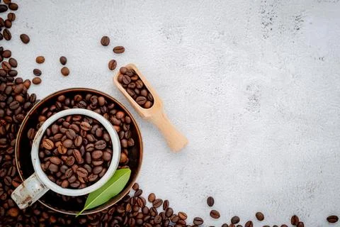 Roasted coffee beans with scoops setup on white concrete background. Stock Photos