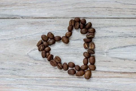 Roasted coffee beans in a shape of a heart on wooden background Stock Photos
