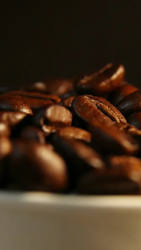 Roasted coffee beans shifting gently in warm soft studio light Stock Footage 323868975