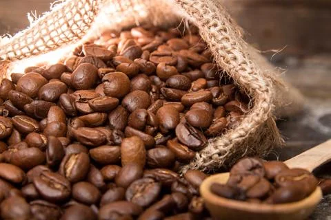Roasted coffee beans in small sack on metal surface Stock Photos