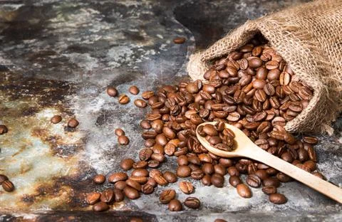 Roasted coffee beans in small sack on metal surface Foto stock