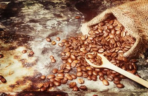 Roasted coffee beans in small sack on metal surface Stock Photos