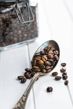Roasted coffee beans in spoon Roasted coffee beans in spoon on white table... Stock Photos