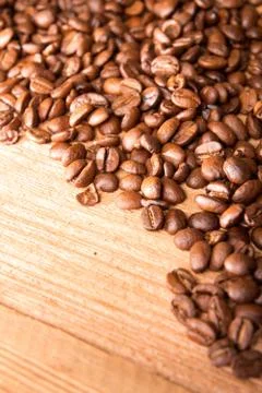 Roasted coffee beans spread over on wooden table. Stock Photos