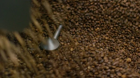 Roasted coffee beans swirling around in cooling tray, in slow motion Free Stock Footage 101199560