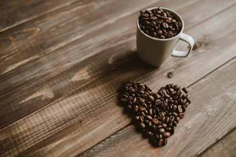 Roasted coffee beans in white cup at wood background and concept coffee love Stock Photos