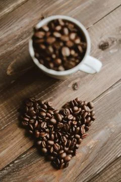 Roasted coffee beans in white cup at wood background and concept coffee love Stock Photos