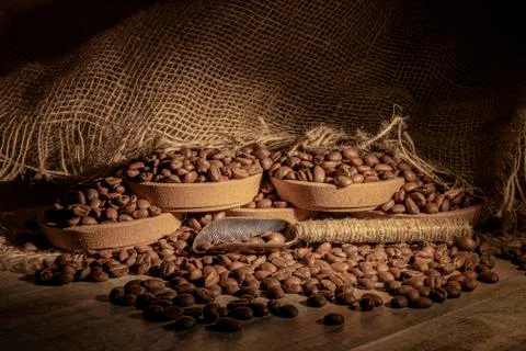 Roasted coffee beans on a wooden table, lying casually in storage plates. Spoon Stock Photos