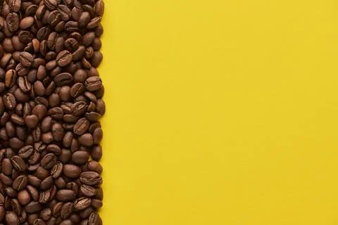 Roasted coffee beans on yellow background with copy space. Close up top view. Stock Photos