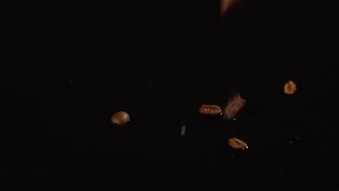 Roasted dark coffee beans falling on a rotating table with wood texture in slow Stock Footage 149896576