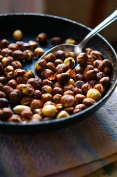 Roasted dried hazelnuts on iron pan with spoon Stock Photos
