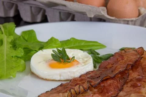 Roasted egg and bacon with fresh vegetables, uncooked eggs on background Фото