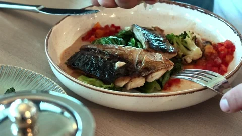 Roasted fish fillets in ceramic bowl with broccoli, leafy greens, diced red Video stock 343516167