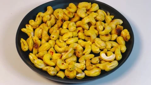 Roasted golden cashew nuts in black plate, top view Stock Footage 336471086