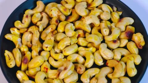 Roasted golden cashew nuts on black presentation plate, top view Stock Footage 336471087
