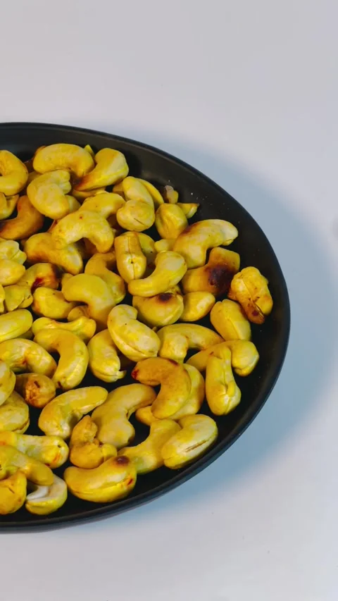 Roasted golden cashew nuts in black plate, top view Stock Footage 336471088