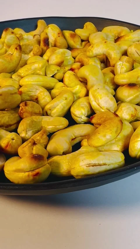 Roasted golden cashew nuts in black plate, close-up shot Stock Footage 336471111