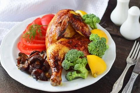 Roasted half chicken with broccoli, tomatoes, fried mushrooms and lemon Stock Photos