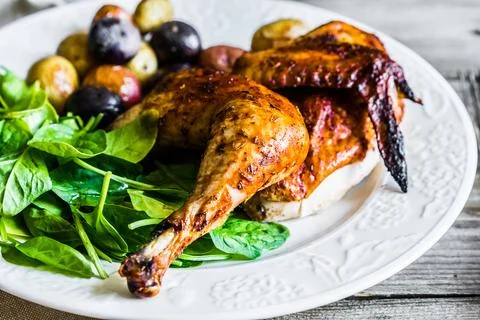 Roasted half chicken with potatoes and spinach Stock Photos