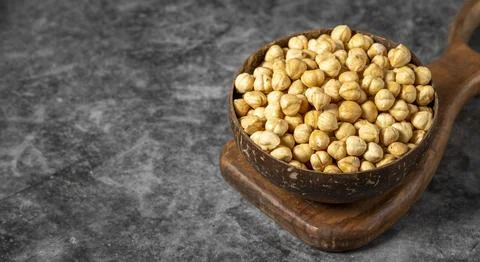 Roasted hazelnut nuts on dark background. Fresh hazelnuts in a coconut bowl.  Stock Photos