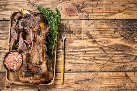 Roasted lamb mutton cutting shoulder meat in a wooden tray with meat fork Stock Photos