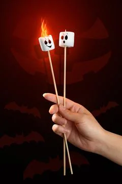 Roasted marshmallow with fire and faces painted on them on halloween scary ba Stock Photos