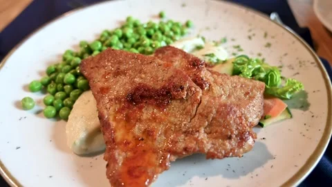 Roasted meat and vegetables served on a plate in a restaurant. Beef and peas. Stock Footage 283686804
