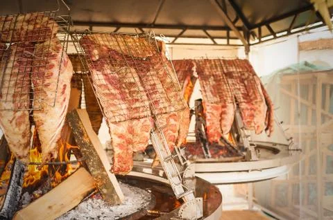 Roasted meat of beef cooked on a vertical grills. Stock Photos