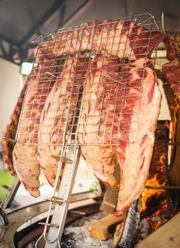 Roasted meat of beef cooked on a vertical grills. Stock Photos