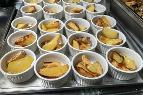 Roasted or baked potatoes in a white bowl, a lot of servings. Stock Photos