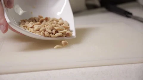Roasted peanuts are poured from a plate onto white cutting board.cooking kitchen Vídeos de archivo 169759706