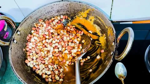 Roasted peanuts mixed with jaggery syrup for indian chikki preparation Stock Photos