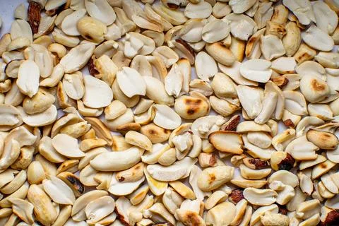 Roasted peanuts separated in two pieces and spread over surface. Stock Photos