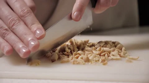 Roasted peanuts on white cutting board. chop the nuts with large knife Stock Footage 169759709
