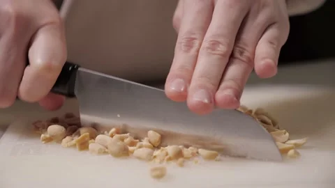 Roasted peanuts on white cutting board. chop the nuts with large knife Stock Footage 169759739