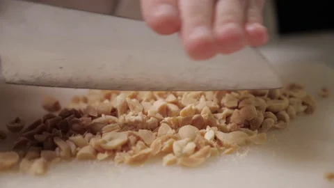 Roasted peanuts on white cutting board. chop the nuts with large knife Stock Footage 169759782