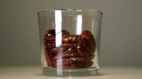Roasted pecans in transparent glass with white reflection Stock Footage 75241524