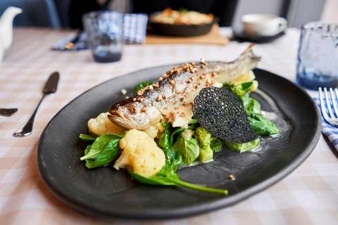 Roasted pike perch or cod fish with baked vegetables and spinach. Dish decorated Foto stock