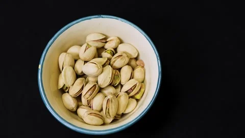 Roasted pistachio nuts in ceramic bowl isolated on black background showcasing Stock Footage 337970144