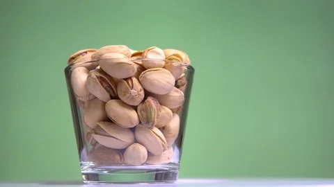 Roasted pistachios in the shell are rotated in the сup on pistachio background Stock Footage 113846800