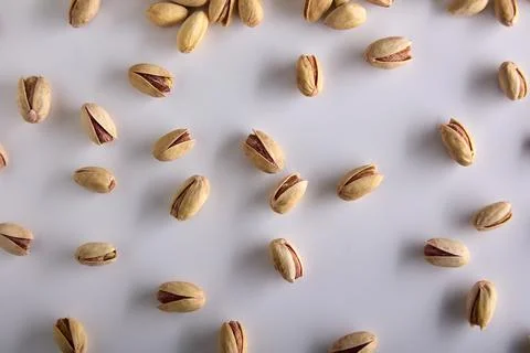Roasted pistachios in the shell on the background of a white table Stock Photos